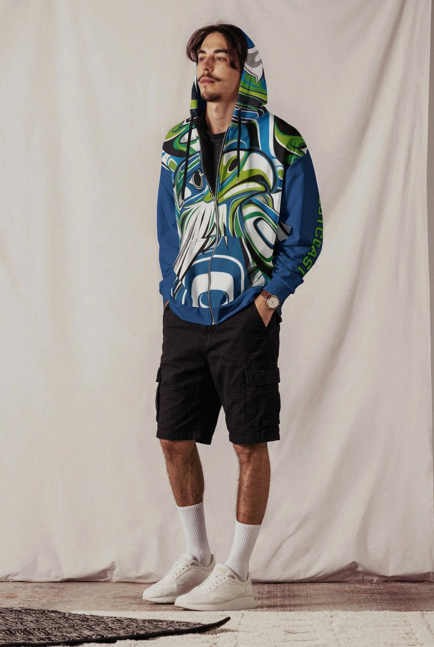 man wearing Zuzuv Pacific Northwest Spirit formline art full-zip hoodie in blue and green with West Coast text on sleeve